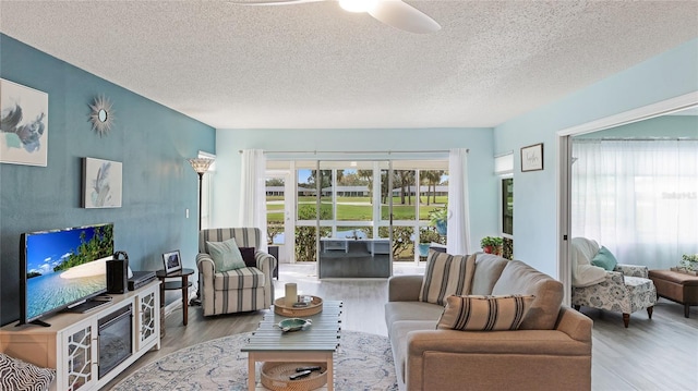 living room featuring a ceiling fan, a textured ceiling, and wood finished floors