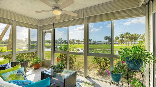 sunroom / solarium with ceiling fan and a water view