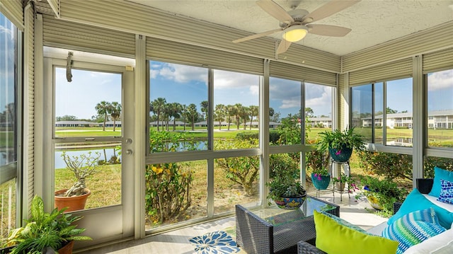 sunroom featuring a water view, a ceiling fan, and a wealth of natural light