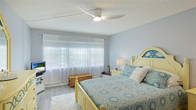 bedroom with a ceiling fan, a textured ceiling, and light wood finished floors