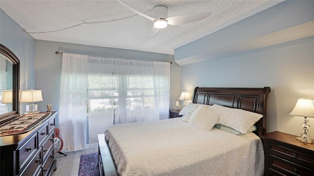 bedroom with ceiling fan, light hardwood / wood-style flooring, and a textured ceiling