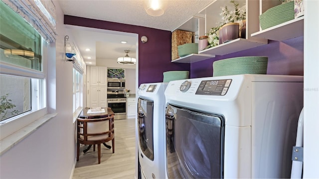 laundry area with light wood finished floors, separate washer and dryer, and a textured ceiling