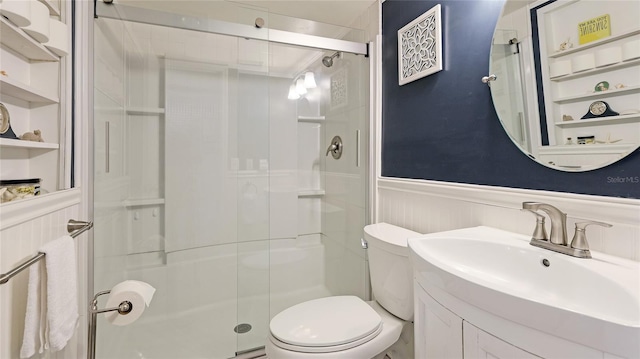 bathroom featuring vanity, a shower with shower door, built in shelves, and toilet