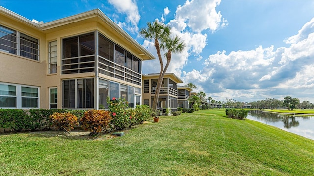 view of yard featuring a sunroom and a water view