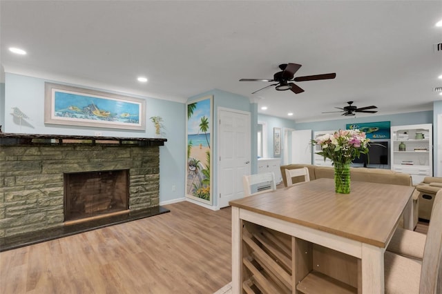 dining area with a stone fireplace and light wood-type flooring