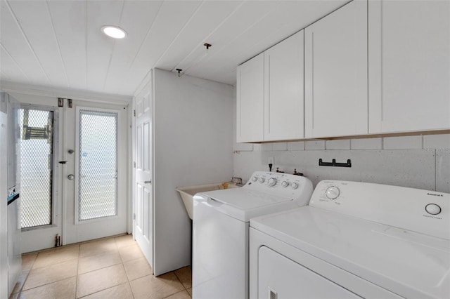 laundry room with light tile patterned flooring, cabinets, sink, and washer and dryer