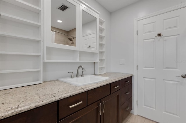 interior space with light stone countertops, sink, light tile patterned floors, and dark brown cabinetry