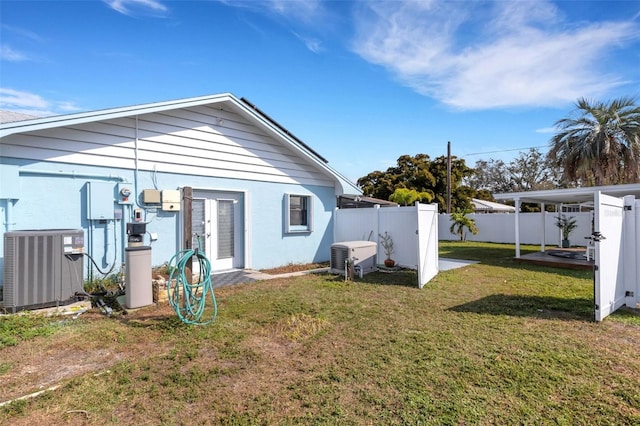 rear view of house featuring cooling unit and a yard