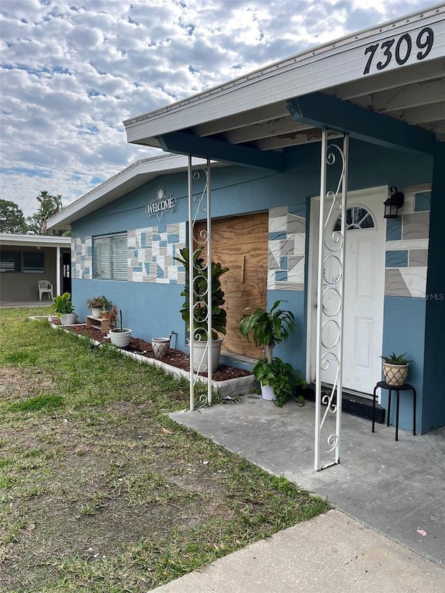 entrance to property featuring a lawn