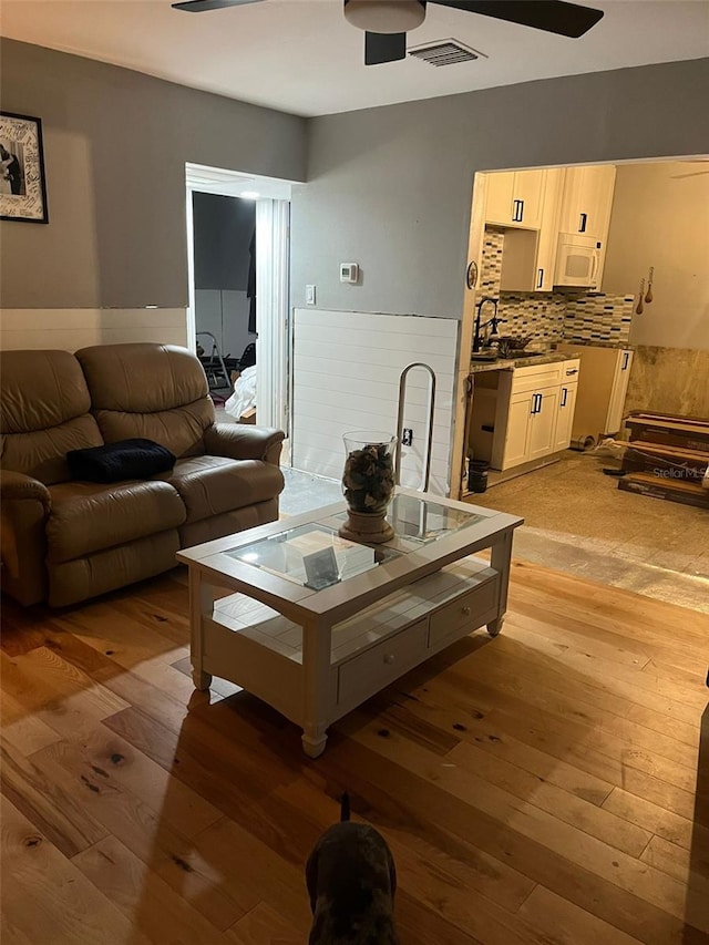 living room with sink, light hardwood / wood-style floors, and ceiling fan