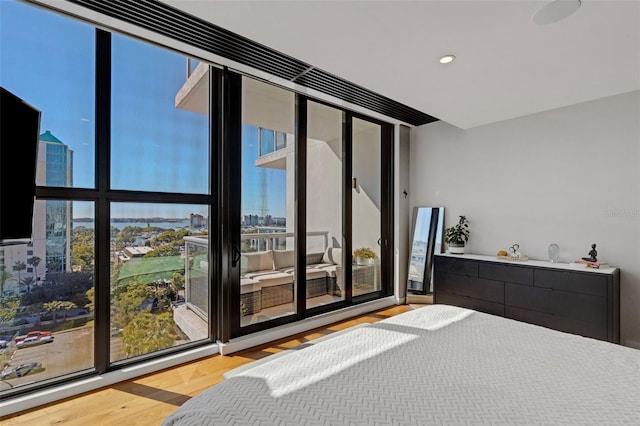 bedroom with multiple windows, hardwood / wood-style floors, and a wall of windows