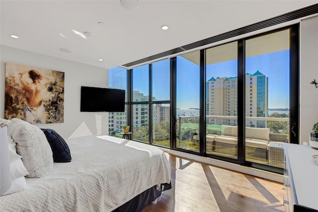 bedroom with expansive windows, wood-type flooring, and multiple windows