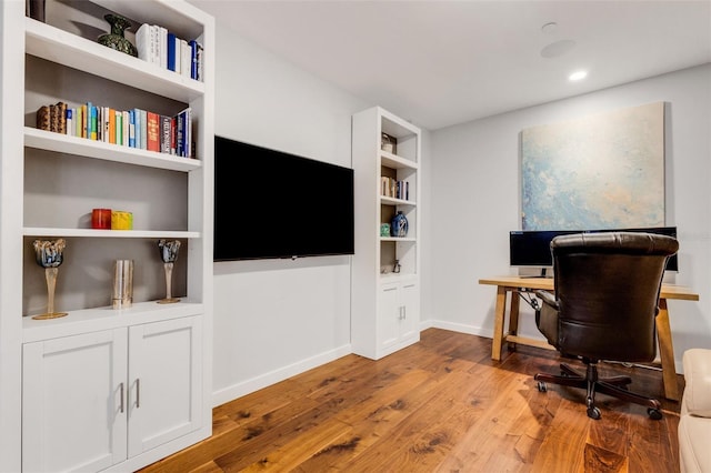 home office featuring light hardwood / wood-style floors and built in shelves