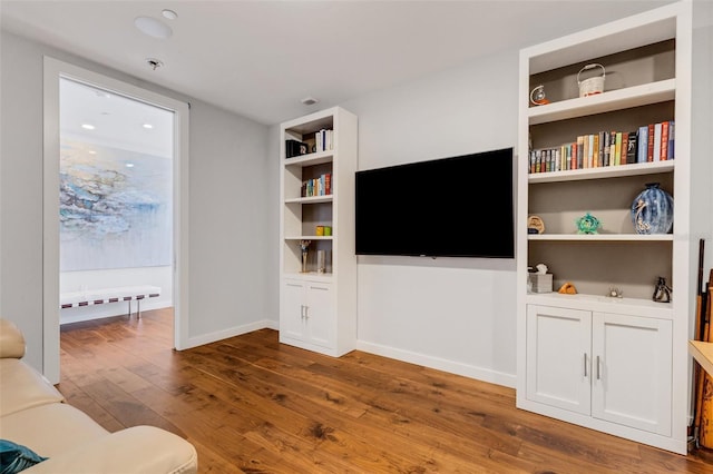 living room featuring built in shelves and dark hardwood / wood-style flooring