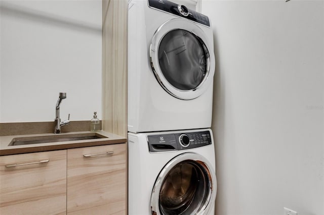 washroom featuring sink, cabinets, and stacked washer / dryer