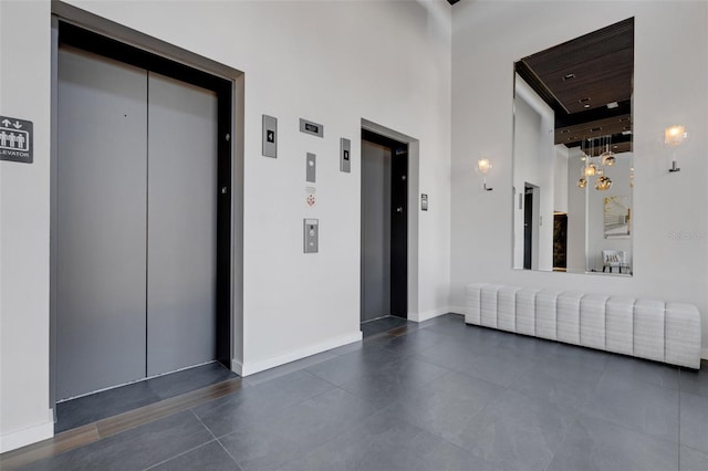 corridor featuring elevator and a high ceiling