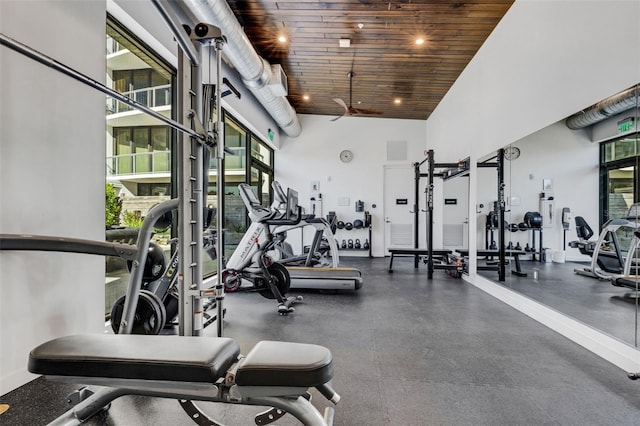 gym featuring wood ceiling, a healthy amount of sunlight, and a high ceiling