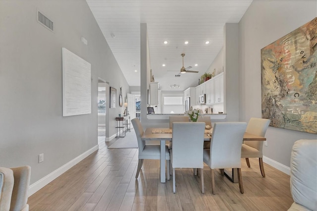 dining room with high vaulted ceiling, ceiling fan, and light wood-type flooring