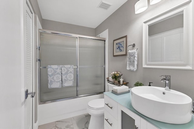 full bathroom with toilet, vanity, and bath / shower combo with glass door