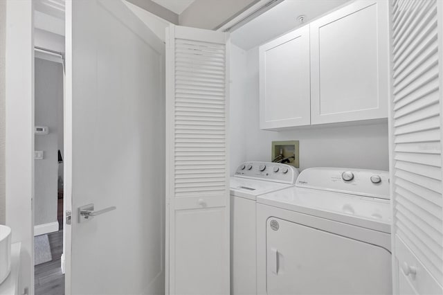 laundry room featuring cabinets, wood-type flooring, and separate washer and dryer