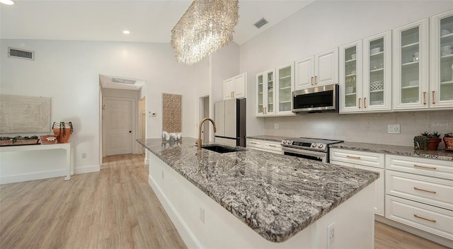 kitchen with white cabinetry, stainless steel appliances, and an island with sink