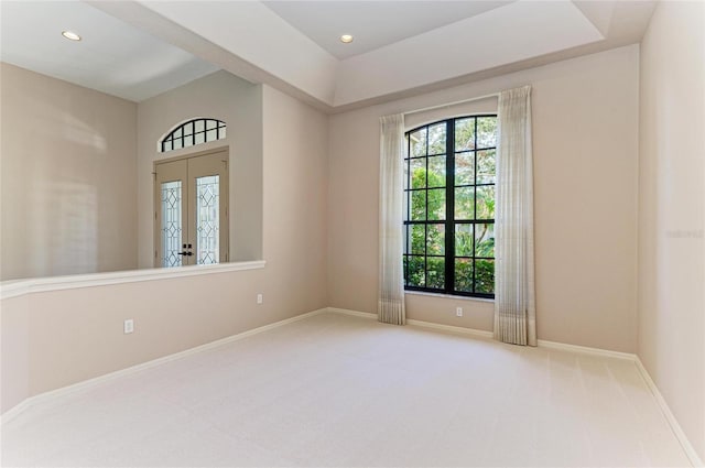 carpeted empty room with a healthy amount of sunlight and french doors