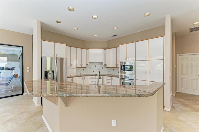 kitchen with appliances with stainless steel finishes, a large island with sink, sink, and white cabinets