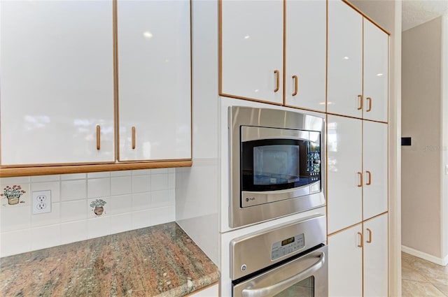 kitchen featuring light tile patterned floors, white cabinetry, stainless steel appliances, light stone counters, and tasteful backsplash