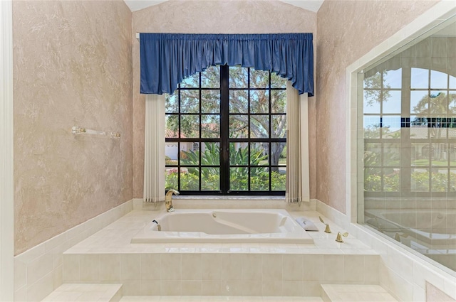 bathroom with tiled tub and vaulted ceiling