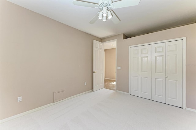 unfurnished bedroom with ceiling fan, light colored carpet, and a closet