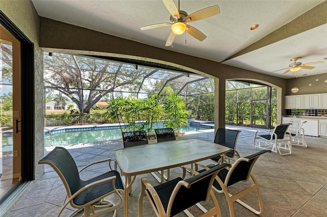 view of patio with ceiling fan, exterior kitchen, and glass enclosure