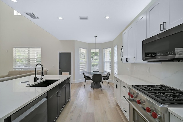 kitchen with stainless steel appliances, hanging light fixtures, sink, and white cabinets