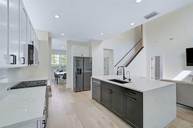 kitchen with white cabinetry, appliances with stainless steel finishes, sink, and light stone counters