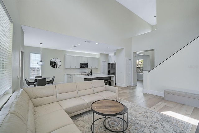 living room featuring sink, plenty of natural light, light hardwood / wood-style floors, and a high ceiling