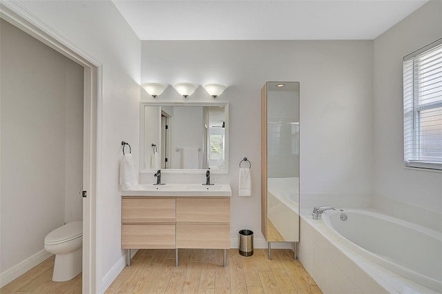 bathroom featuring a relaxing tiled tub, vanity, toilet, and hardwood / wood-style floors