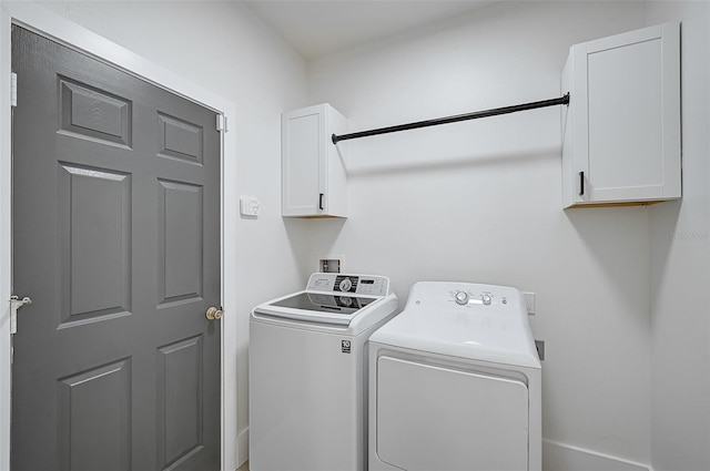 clothes washing area featuring washer and clothes dryer and cabinets