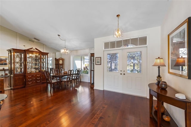 entryway featuring lofted ceiling, dark wood-type flooring, french doors, and a chandelier