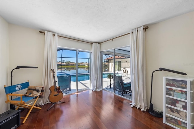 workout area featuring dark hardwood / wood-style floors, a textured ceiling, and a water view