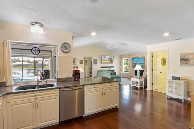 kitchen with sink, dark wood-type flooring, dark stone countertops, vaulted ceiling, and stainless steel dishwasher