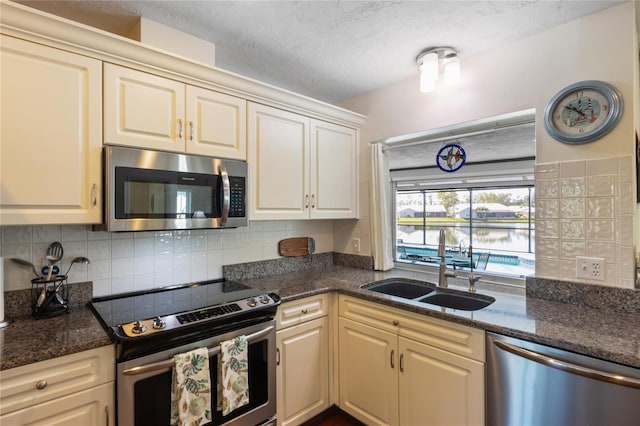 kitchen featuring stainless steel appliances, cream cabinets, sink, and decorative backsplash