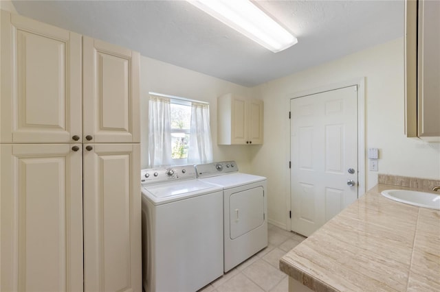 laundry area featuring cabinets, washing machine and clothes dryer, sink, and light tile patterned floors