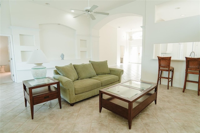 tiled living room featuring ceiling fan and a high ceiling