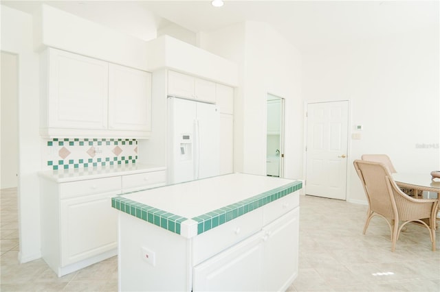 kitchen with decorative backsplash, white cabinets, a kitchen island, and white fridge with ice dispenser