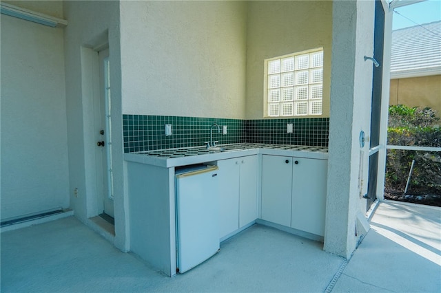 kitchen with backsplash, dishwashing machine, sink, and white cabinets