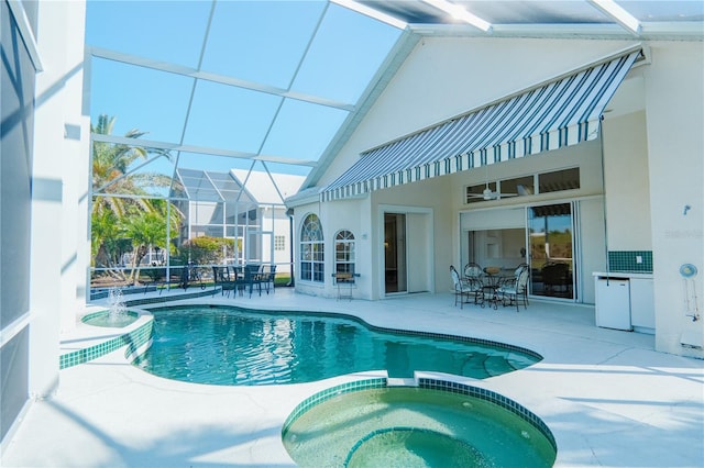 view of pool featuring pool water feature, a patio, glass enclosure, and an in ground hot tub