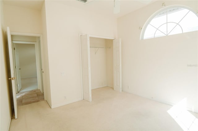 unfurnished bedroom featuring light colored carpet and a closet