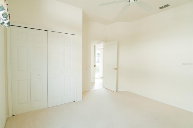 unfurnished bedroom with ceiling fan, light colored carpet, and a closet