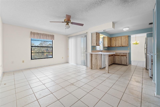 kitchen featuring light tile patterned floors, dishwasher, a textured ceiling, ceiling fan with notable chandelier, and kitchen peninsula