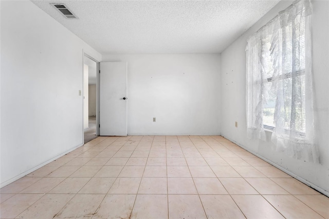 tiled spare room with a textured ceiling