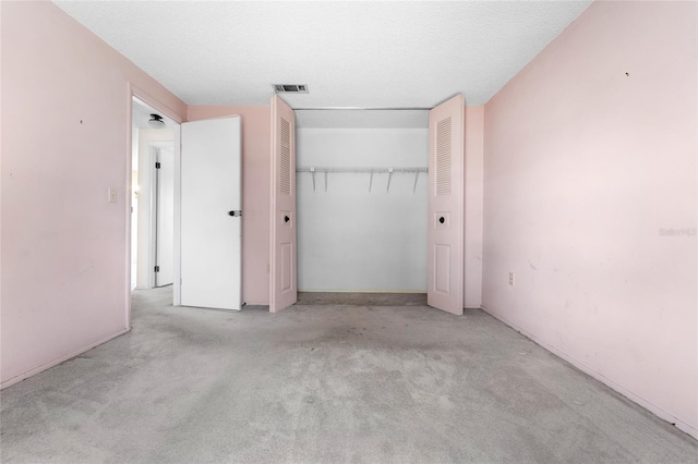 unfurnished bedroom with light colored carpet, a textured ceiling, and a closet